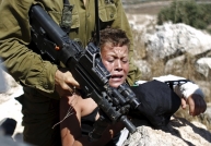 An Israeli soldier detains a Palestinian boy during a protest in the West Bank village of Nabi Saleh in August. (Mohamad Torokman/Reuters)